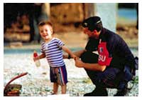 Un carabiniere gioca con un bambino straniero.